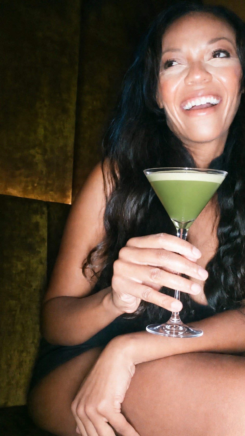 jenna laughing in a velvet booth holding a green matcha martini